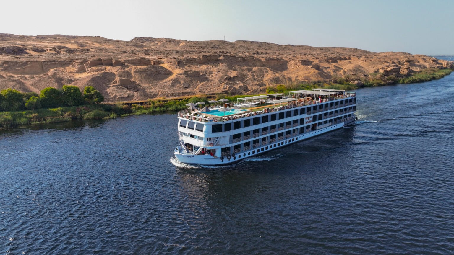 City and Sea Adonis cruising the Nile River past ancient Egyptian ruins and green riverbanks.