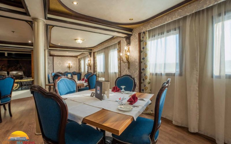 Elegant dining room aboard the M/S City & Sea Adonis with blue velvet chairs and river views.