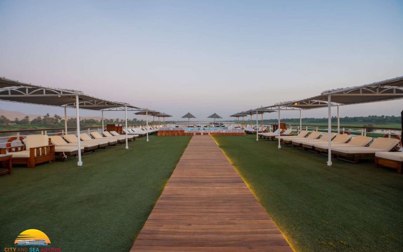Sun deck aboard the M/S City & Sea Adonis with loungers, umbrellas and Nile views at dusk.