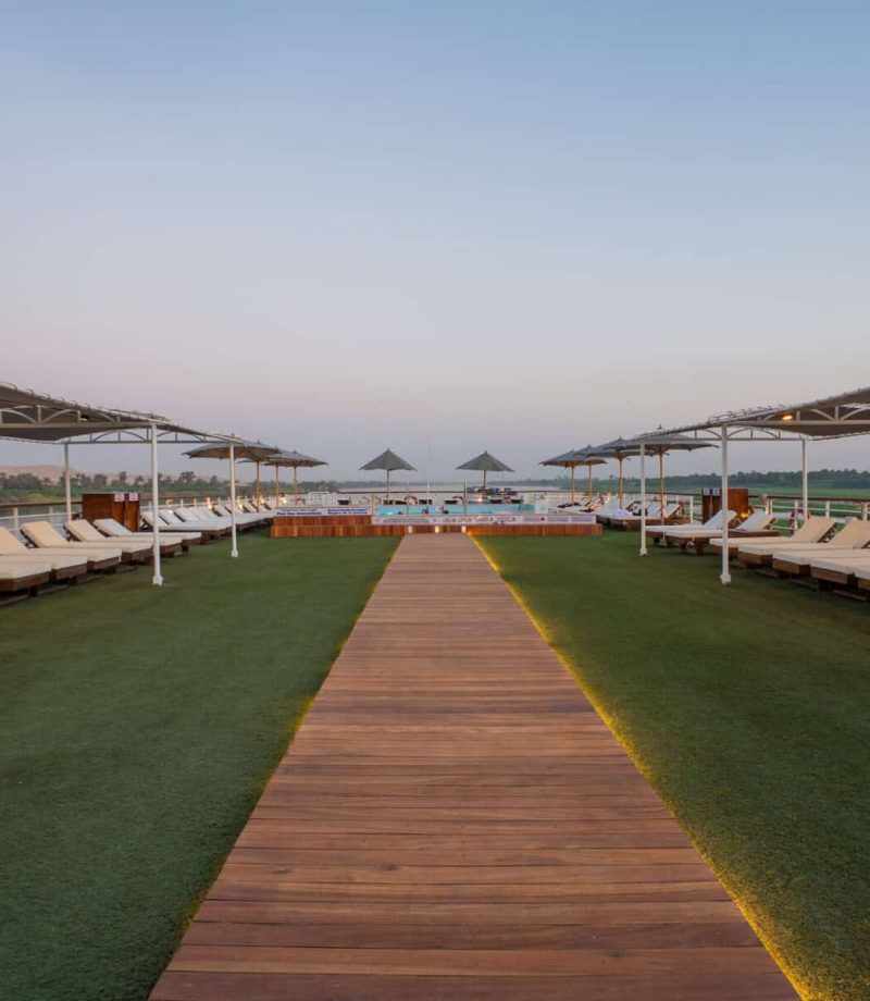 Sun deck aboard the M/S City & Sea Adonis with loungers, umbrellas and Nile views at dusk.