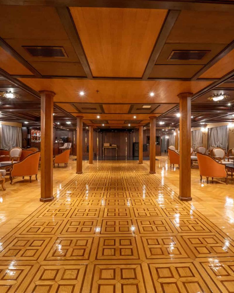 Spacious lounge aboard the M/S City & Sea Adonis with wooden ceiling, elegant seating and polished parquet flooring.
