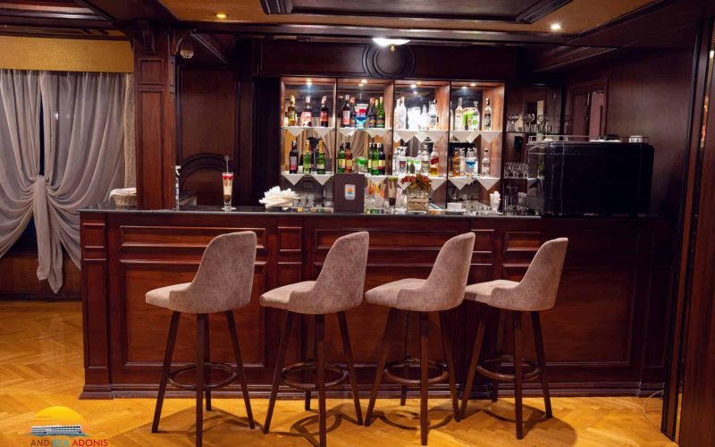 Elegant bar lounge aboard the M/S City & Sea Adonis with wood paneling and upholstered seating.