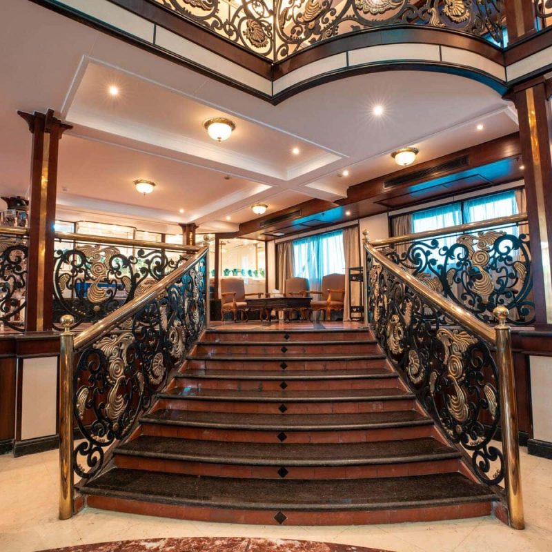 Grand staircase with ornate brass railings aboard the M/S City & Sea Adonis Nile cruise ship.