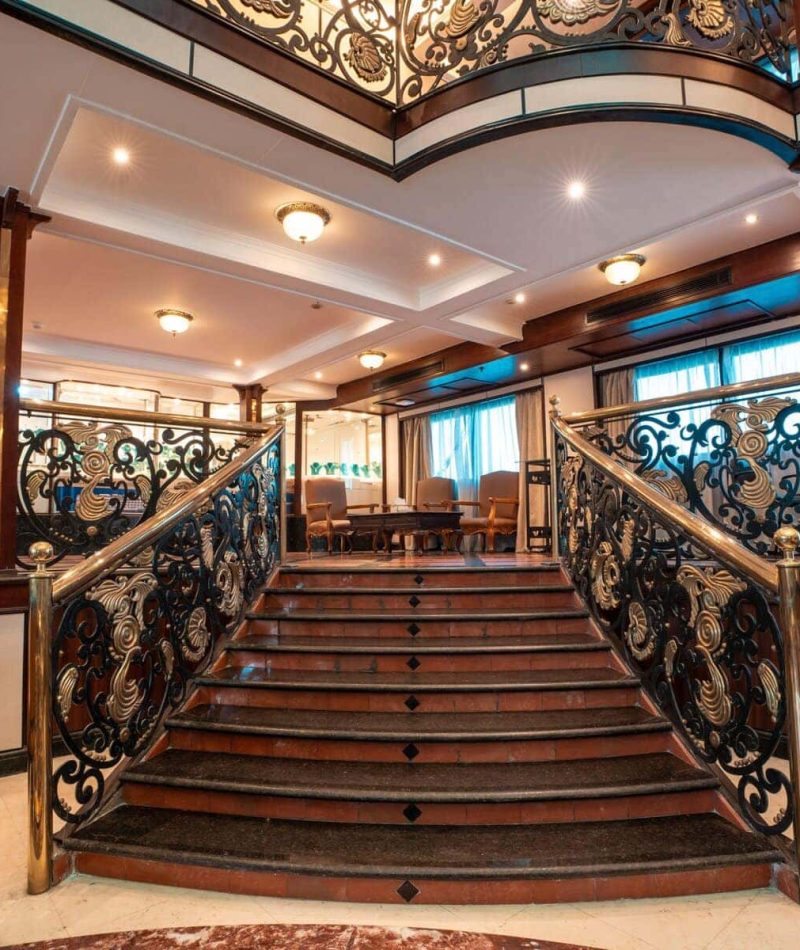 Grand staircase with ornate brass railings aboard the M/S City & Sea Adonis Nile cruise ship.