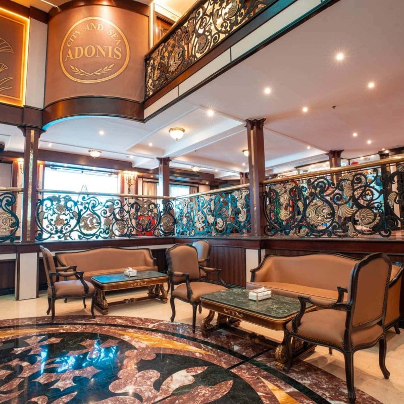 Elegant lounge aboard the M/S City & Sea Adonis with ornate railings and Egyptian-inspired decor.