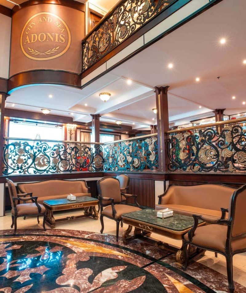 Elegant lounge aboard the M/S City & Sea Adonis with ornate railings and Egyptian-inspired decor.