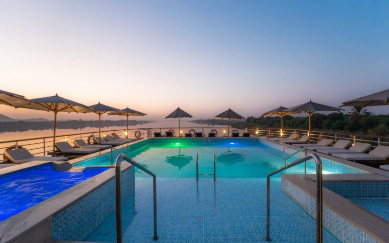 Illuminated pool deck aboard M/S City & Sea Adonis at dusk overlooking the Nile River.