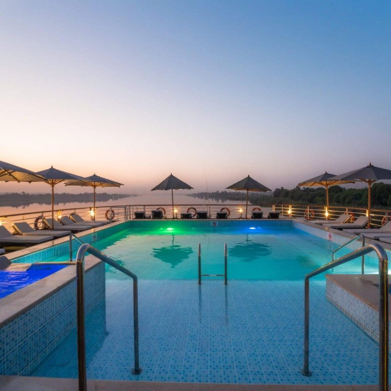 Illuminated pool deck aboard M/S City & Sea Adonis at dusk overlooking the Nile River.
