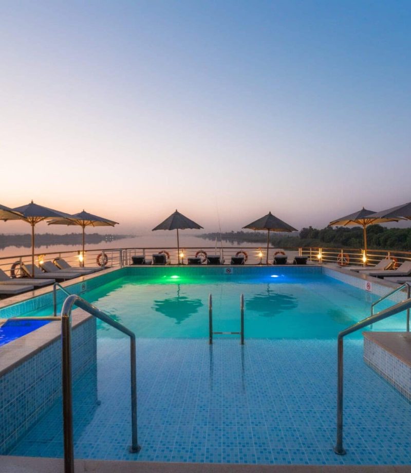 Illuminated pool deck aboard M/S City & Sea Adonis at dusk overlooking the Nile River.