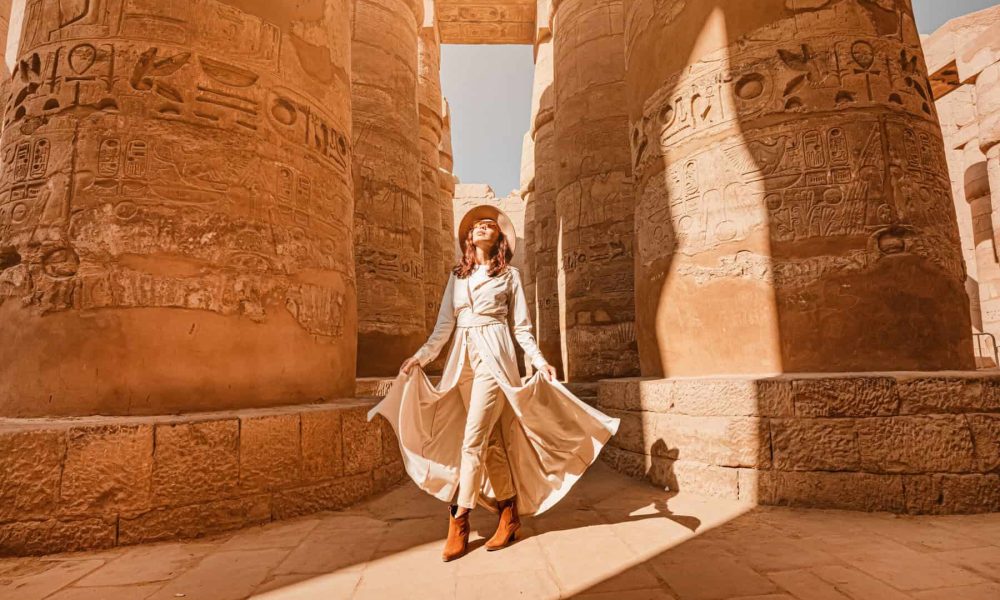 Woman traveler explores the ruins of the ancient Karnak temple in the city of Luxor in Egypt. Great row of columns with carved hieroglyph